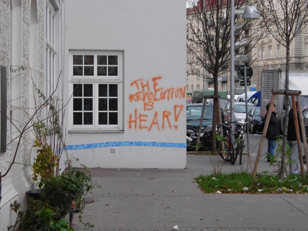 © Ostermayer Hausfassade mit einem Graffiti "The Revolution Is Hear"