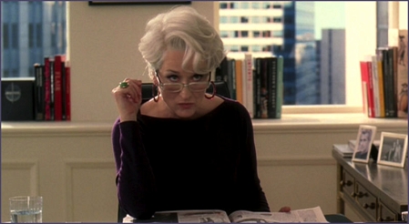 Meryl Streep an einem Schreibtisch sitzend in "The Devil wears Prada"