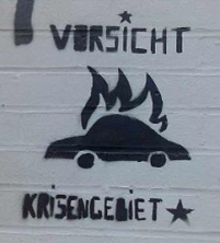 Stencil "Vorsicht Krisengebiet" mit brennendem Auto