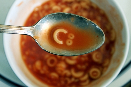 Suppe im Löffel mit Nudeln, die "C:" formen