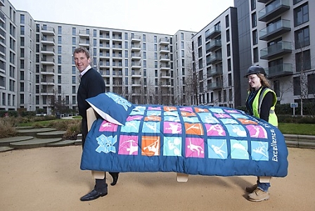 Olympic gold medallist Matthew Pinsent and friend carrying the first of 16,000 beds to be installed in the Olympic Village 