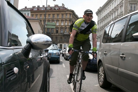 Fahradbote zwischen Häuserzeilen und PKW