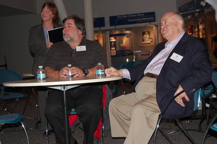 Steve Wozniak und Jack Tramiel sitzen nebeneinander an einem Tisch.