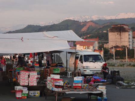 Marktplatz in der Morgensonne, dahinter schneebedeckte Bergkette