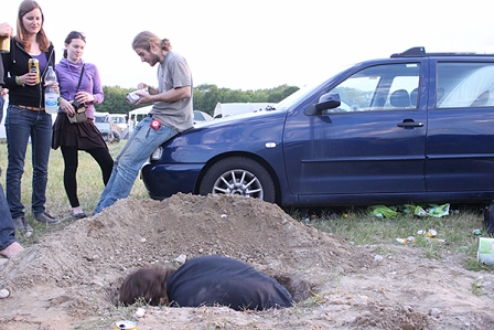 ein Festivalbesucher gräbt ein Loch und andere schauen zu