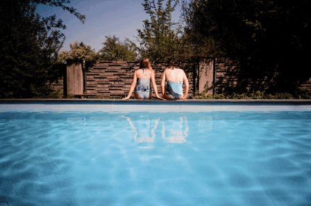 blauer pool, 2 mädchen mit dem rücken zu uns, 