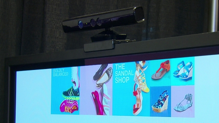 Ein Monitor zeigt einen Online-Schuh-Shop an, darüber ist ein Kinect-Gerät montiert.