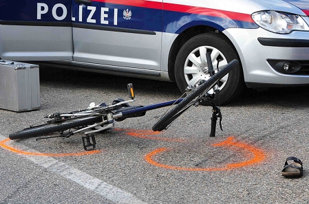 Unfall mit Fahrrad, Polizeiauto im Hintergrund, Schlapfen