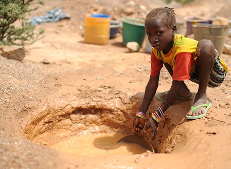 Kinderarbeit, schwarzes Mädchen wäscht in verdrecktem Wasser.