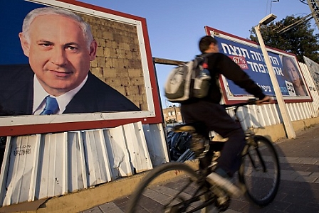 An Israeli cycles past election posters showing the right-wing  Likud party with current Israeli Prime Minister Benjamin Netanyahu (L) and the Hatnuah (Movement) party showing centrist Tzipi Livni