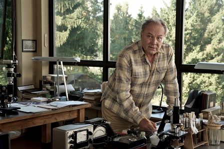 Klaus Maria Brandauer im Flanelhemd in einem Zimmer