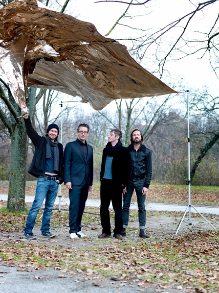 Die Band Naked Lunch in einem herbstlichen Park unter einer wehenden Goldfolie