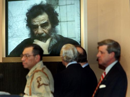 A video image of a haggard and bearded Saddam Hussein is shown during a press conference where US Administrator to Iraq, Paul Bremer (R) announced that "We Got Him!". 