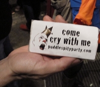 Eine Hand hält ein Taschentuchpackerl mit einem aufgezeichneten Weißclown und der Aufschrift "Come cry with me"