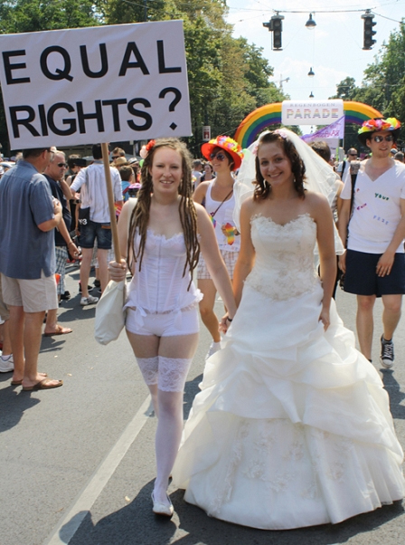 Zwei Frauen im Hochzeitskleid, mit Schild "Equal Rights?"