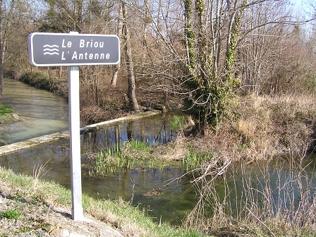 Ein kleiner Bach bzw. ein Teich, daneben ein Schild, auf dem steht "Le Briou / L'Antenne".