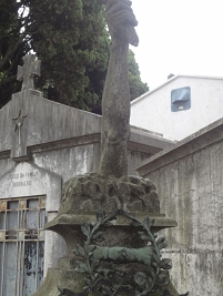 Ein steinener Arm, der aus einem Grabstein herausragt.