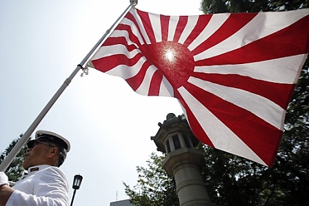 A man dressed as a navy sailor holds the Japanese military Rising Sun flag at Yasukuni Shrine, on the 68th anniversary of the end of World War II, in Tokyo, Japan, 15 August 2013