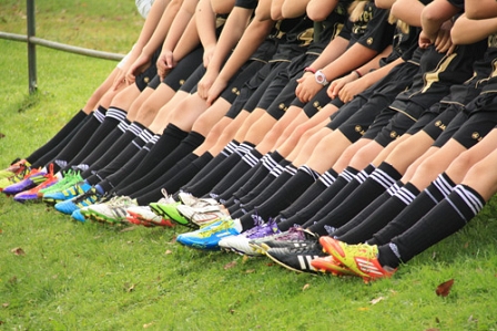 Fußballmannschaft in schwarzen Dressen mit bunten Fußballschuhen