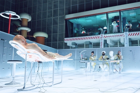 Christoph Waltz mit Glatze auf einem futuristischen Krankenbett im Film "The Zero Theorem".