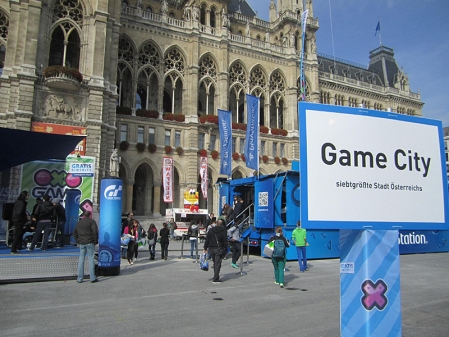 Das Wiener Rathaus, davor ein paar Videospielstände. Im Vordergrund rechts ein großes Schild, auf dem "Game City. Siebtgrößte Stadt Österreichs" steht.