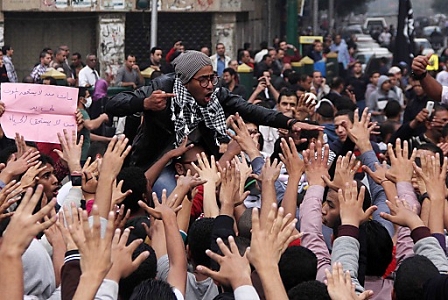 Egyptian students hold a small poster denouncing the death of their comrade about one week earlier as they protest in Tahrir square, Cairo, Egypt, 01 December 2013