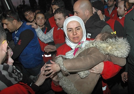  A Syrian woman carries a child as Syrian Red Crescent workers offer help at a shelter center in Homs, Syria, 10 February 2014