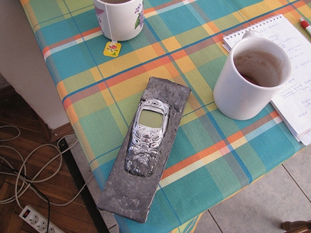 Ein altes Handy in Eisen gegossen liegt am Kaffeetisch