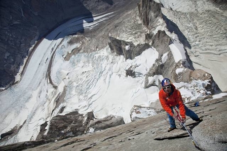 Kletterer David Lama hängt am Seil in einer Felswand. Unter ihm vor allem Gletscher