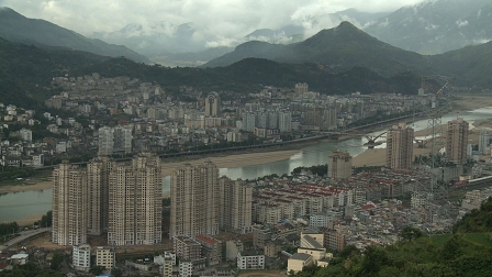 Eine chinesische Stadt, Wolkenkratzer an einem Flussufer. Filmstill aus der Dokumentation "China Reverse".