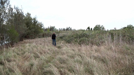 Frau mit Pendel steht im Gebüsch