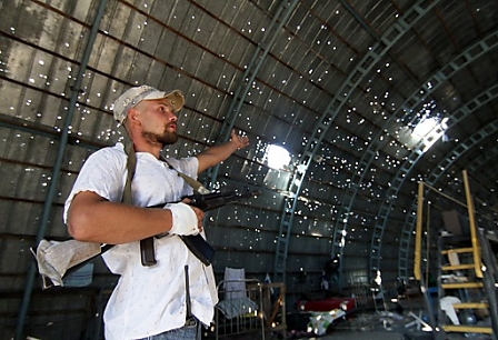 A volunteer of the Ukrainian army shows a destroyed roof of a hangar at the checkpoint 'Novoazovsk' on the Ukrainian-Russian border in the Novoazovsk district, Donetsk region.