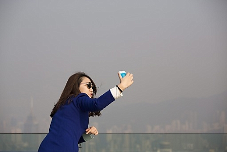 A woman take a 'selfie' during a visit to Victoria Peak as a pollution haze covers Victoria Harbour in Hong Kong, China