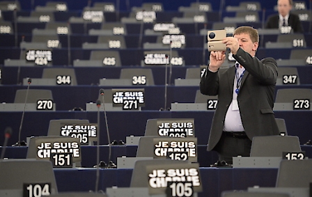 A delegate takes images with his smartphone while signs reading 'Je Suis Charlie' (I am Charlie) stand on parliamentarians' desk at the European Parliment in Strasbourg, France, 13 January 2015