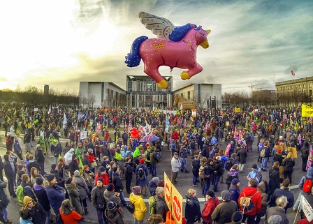 DemonstrantInnen mit einem großen Luftballon, der ein fliegendes rosa Pferd darstellt