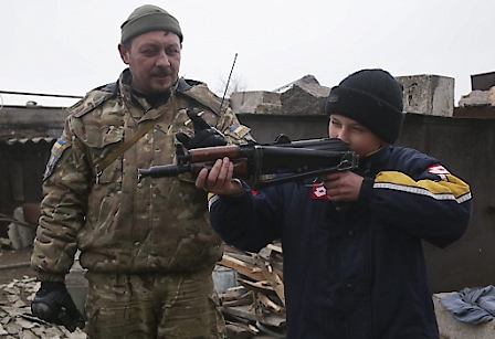 A local boy looks at the sight of a weapon given to him by a Ukrainian serviceman.