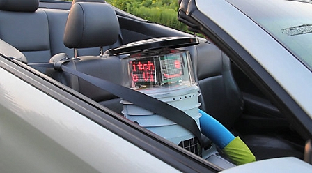 hitchBOT sitting in the passenger seat of a car after hitching a ride. A trivia-loving, wellington-wearing, tweeting robot  hitchhiked across Canada last summer, one ride at a time. 