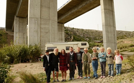 Zehnköpfige Familie steht nebeneinander und sich umarmend vor ihrem Zuhause, einem Wohnmobil