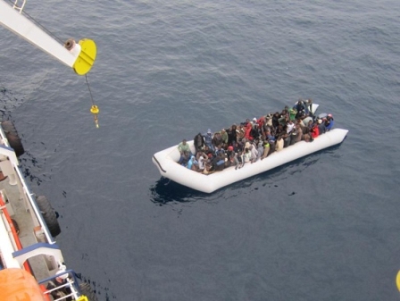 A boat with refugees next to the cargo ship 'OOC¦Cougar' in the Mediterranean sea on 17 January 2015