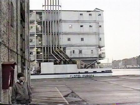 Ein Bub steht vor einem großen Schiff. Filmstill aus "Flotel Europa"