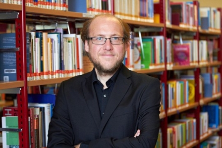 Mann mit Brille vor einer Bücherwand