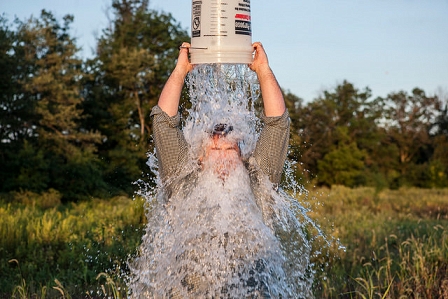 Mann schüttet sich einen Kübel Wasser über den Kopf