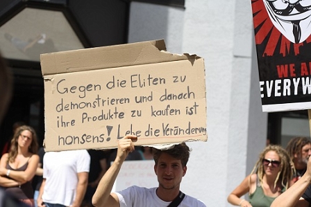 Ein Demonstrant mit dem Schild: Gegen die Eliten zu demonstrieren und danach ihre Produkte zu kaufen ist nonsens! Lebe die Veränderung