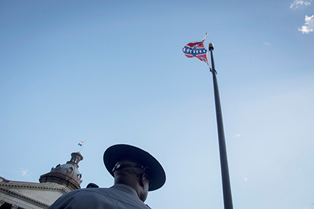 © APA/EPA/JOHN TAGGART Die gehisste Flagge der Konföderierten Staaten von Amerika, darunter eine Art Sheriff von hinten.
