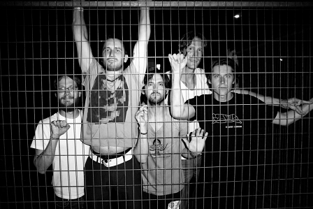 Die Band "Desaparecidos" in schwarz-weiß hinter einem Metallzaun.