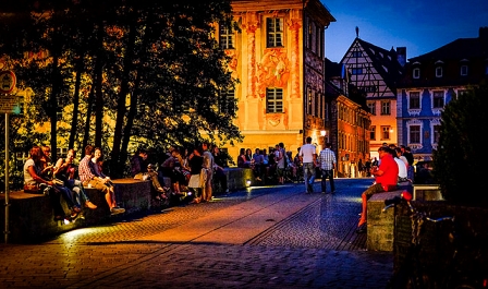 Menschen sitzen auf der Straße am Abend und trinken etwas