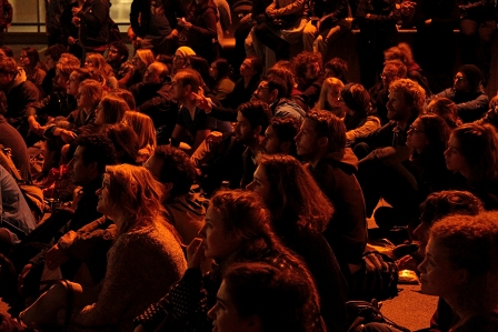 Publikum sitzt in einem Hinterhof bei einer der "Kurzfilmwanderungen" im Freien in der Nacht in Graz