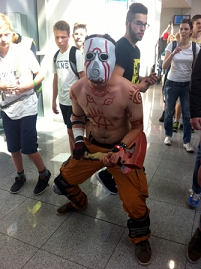 Cosplayer mit Maske, Axt und Körperbemalung.