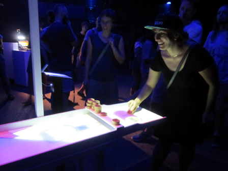 Eine junge Frau spielt lachend ein Shuffleboard-Spiel am Platine Cologne Festival.