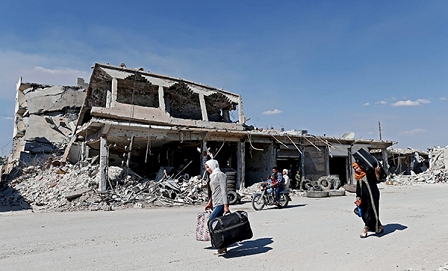 © APA/EPA/SEDAT SUNA Frauen mit Gepäck vor einem zerstörten Haus in Kobane